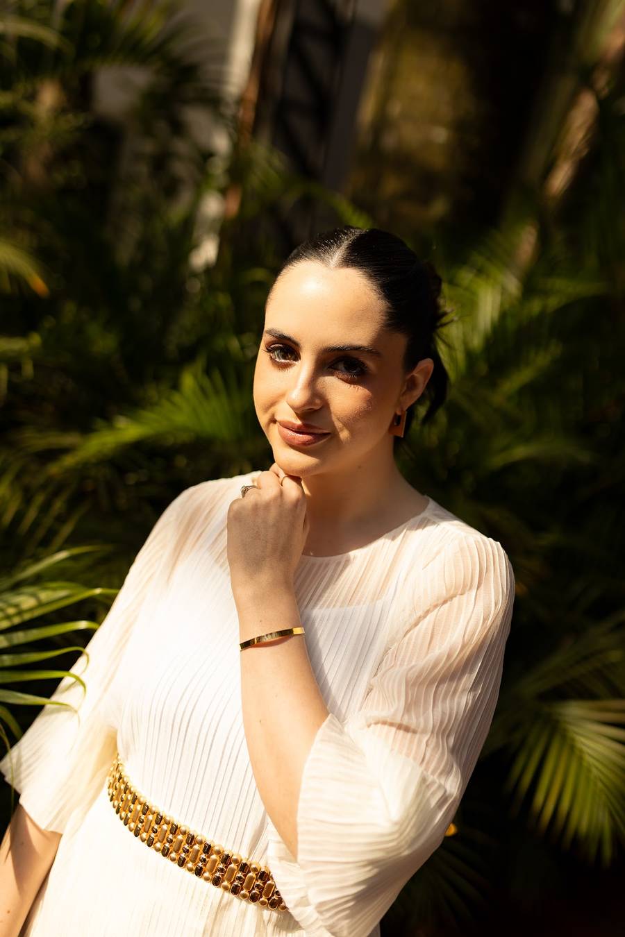 Retrato de Marcela Lamastra de blusa branca, em meio a folhagens