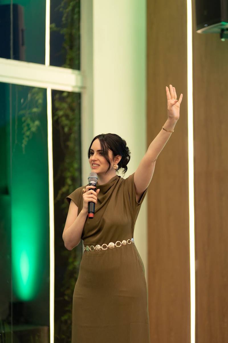 Marcela no palco, de microfone na mão e braço erguido